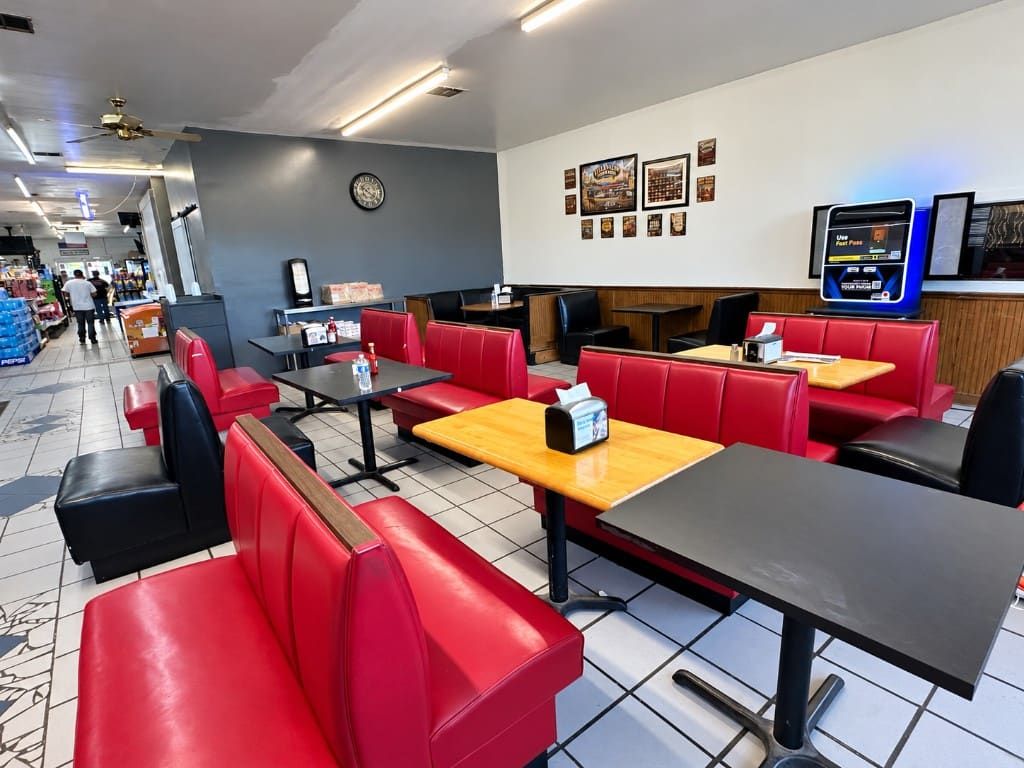 Hillview dining room with red booths, black tables, and the convenience store beyond